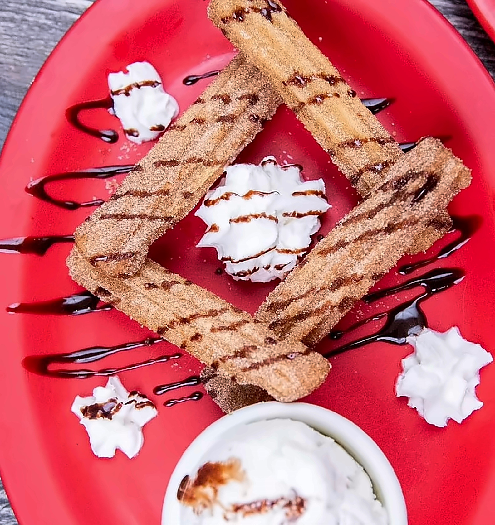 Churros with chocolate drizzle, whipped cream and ice cream